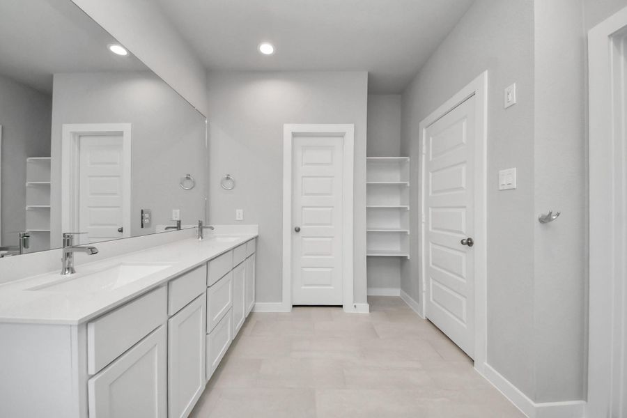 Elevate your daily routine at the elegant vanity, now equipped with double sinks, light countertops, modern hardware, and beautiful recessed lights.