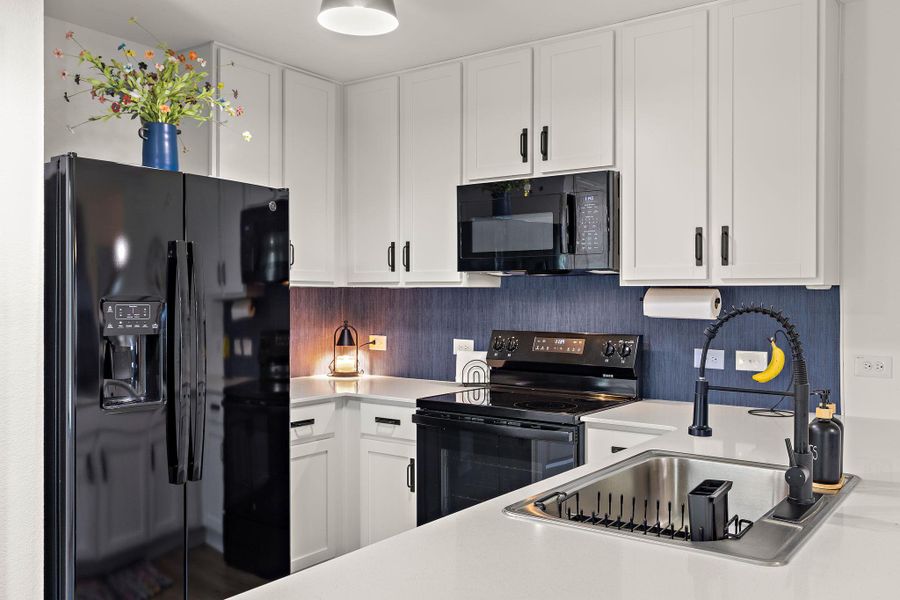 A contemporary kitchen showcasing sleek black appliances contrasting with crisp white cabinetry and bright countertops. A contemporary kitchen showcasing sleek black appliances contrasting with crisp white cabinetry and bright countertops.