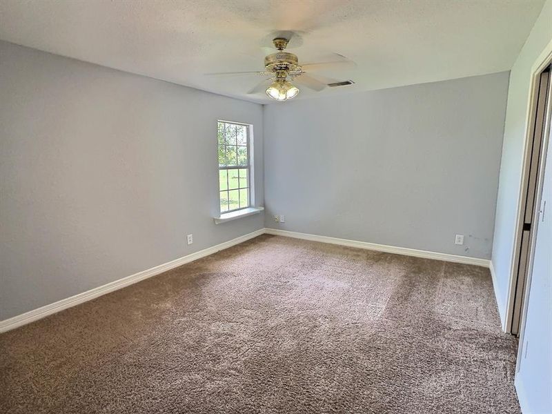 Carpeted bedroom with ceiling fan and baseboards