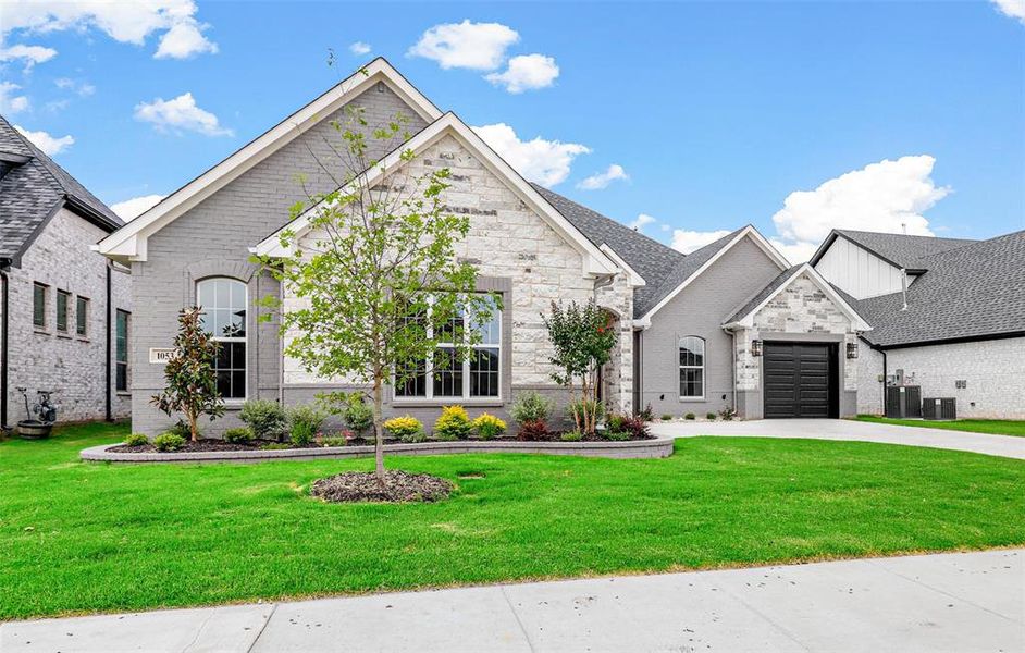 French country home featuring a front yard and a garage