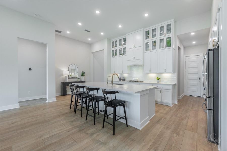 This showstopping kitchen is anchored by an expansive quartz island with breakfast bar. Floor-to-ceiling cabinetry, glass-front displays and warm gold hardware create an unforgettable luxury statement. This showstopping kitchen is anchored by an expansive quartz island with breakfast bar. Floor-to-ceiling cabinetry, glass-front displays and warm gold hardware create an unforgettable luxury statement.