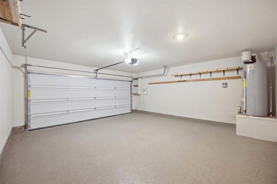 An immaculate attached garage showcases durable epoxy flooring and convenient overhead storage options.