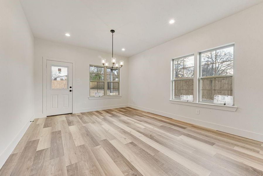 Unfurnished dining area with light wood finished floors, a chandelier, and recessed lighting Unfurnished dining area with light wood finished floors, a chandelier, and recessed lighting