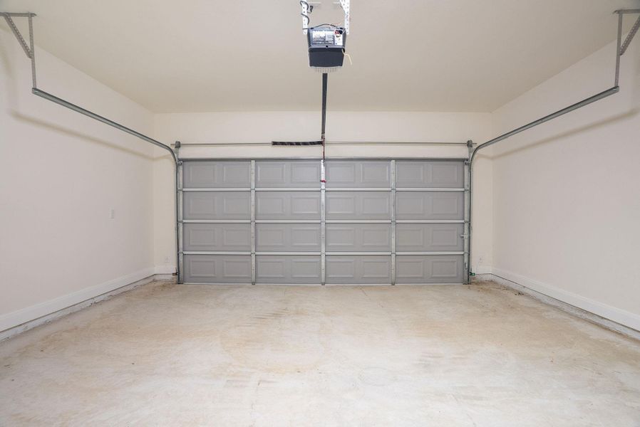 Garage with baseboards and a garage door opener Garage with baseboards and a garage door opener