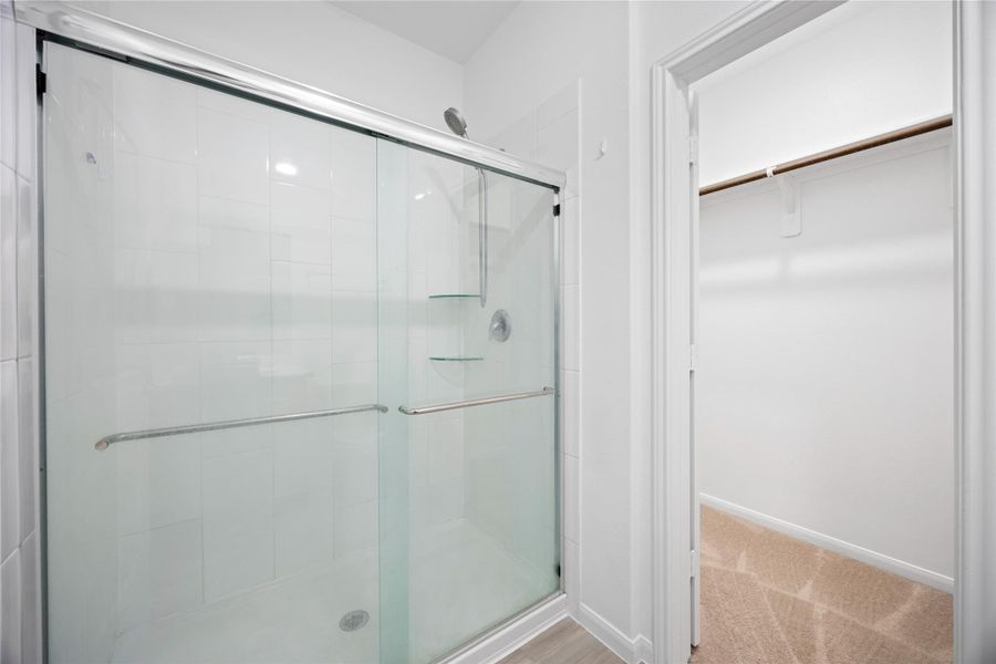 Modern bathroom with a glass-enclosed shower and adjacent spacious walk-in closet.