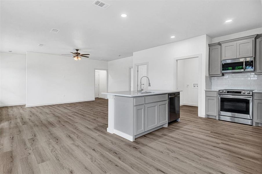 Kitchen featuring cabinetry, tasteful backsplash, light wood finished floors, recessed lighting, and appliances with stainless steel finishes