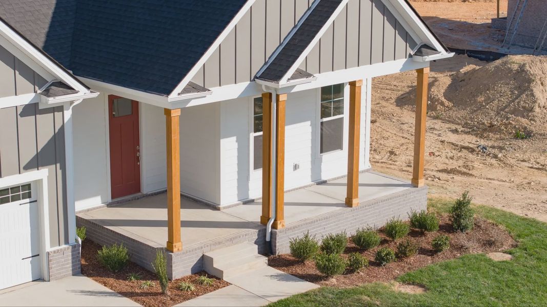 Exterior of home with white and gray siding and wood accent columns around covered front porch