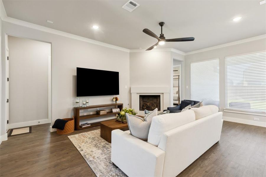 Living room with ornamental molding, ceiling fan, and dark wood-type flooring