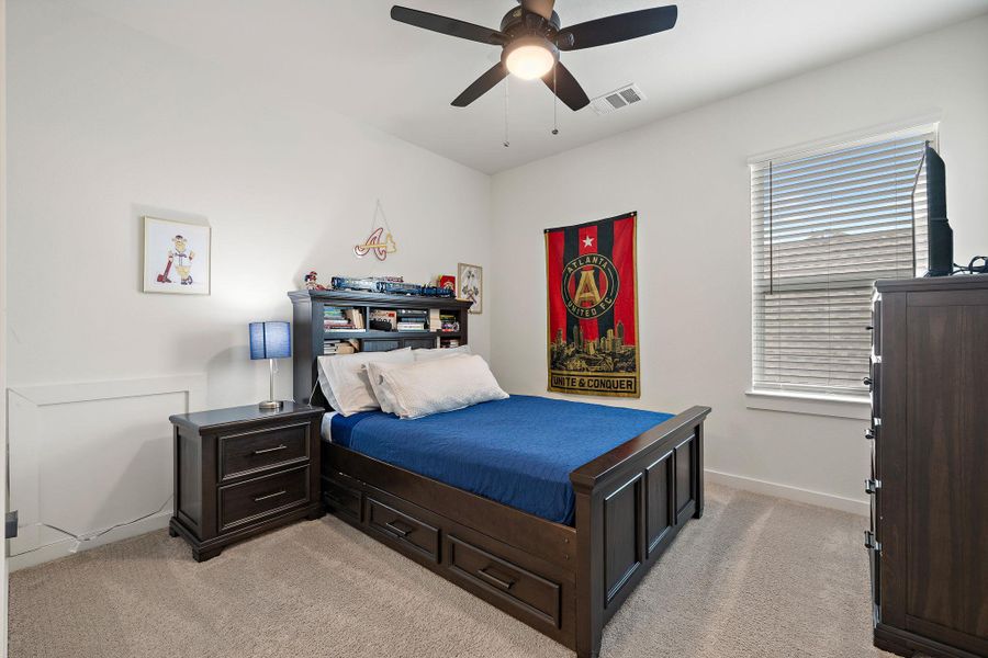 Carpeted interior room featuring a ceiling fan with integrated lighting, a window with horizontal blinds, and white painted walls with trim detailing