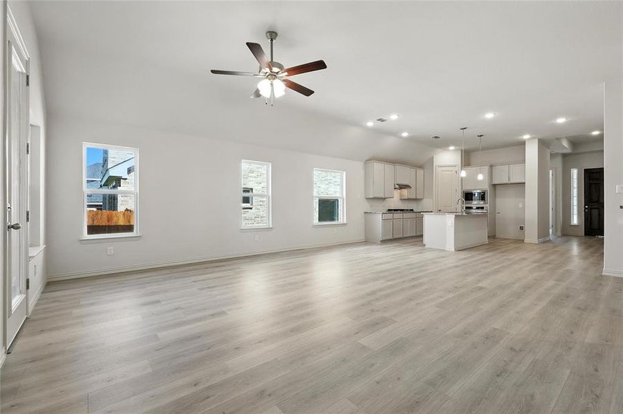 Unfurnished living room with recessed lighting, a ceiling fan, light wood-style flooring, and vaulted ceiling Unfurnished living room with recessed lighting, a ceiling fan, light wood-style flooring, and vaulted ceiling