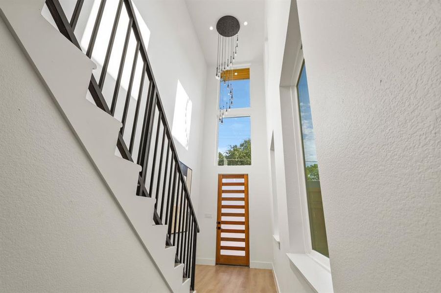 Entryway with a towering ceiling, an inviting chandelier, and light hardwood / wood-style flooring