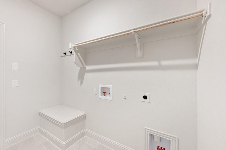 Laundry room with white walls, wall-mounted shelf, washer hookups, and a small bench Laundry room with white walls, wall-mounted shelf, washer hookups, and a small bench