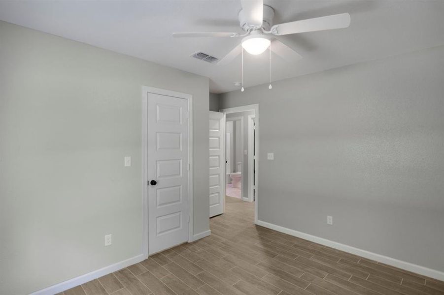 Unfurnished bedroom with wood finish floors and a ceiling fan Unfurnished bedroom with wood finish floors and a ceiling fan