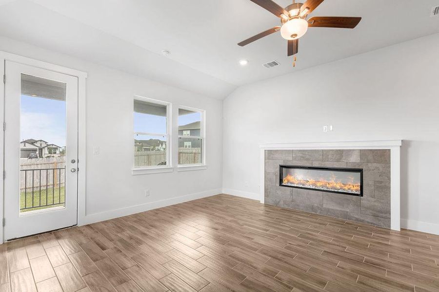 A well-lit living area features warm wood-look flooring and a modern linear fireplace. A well-lit living area features warm wood-look flooring and a modern linear fireplace.