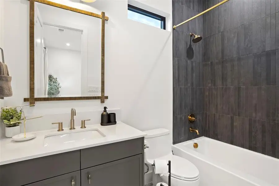Bathroom with a white vanity featuring a rectangular undermount sink and brushed brass fixtures, complemented by a white countertop