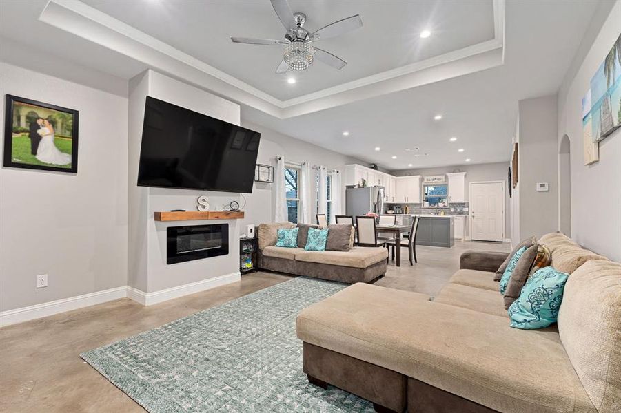 Living room with a raised ceiling, ornamental molding, and ceiling fan