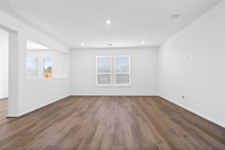 Bring family and friends together in this beautiful Great Room! It features high ceilings, recessed lighting, custom paint, stunning vinyl plank flooring, and large windows that fill the space with natural light all day long.