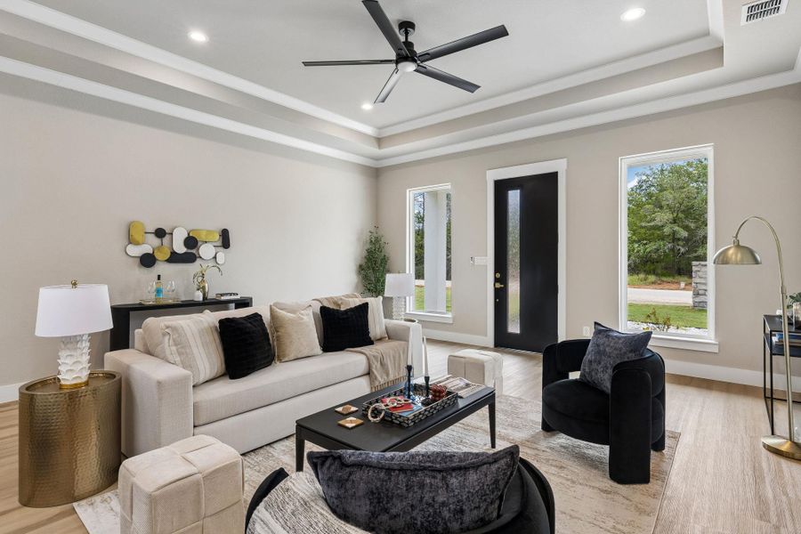 The living area presents elegant tray ceilings and recessed lighting, creating a comfortable gathering space.