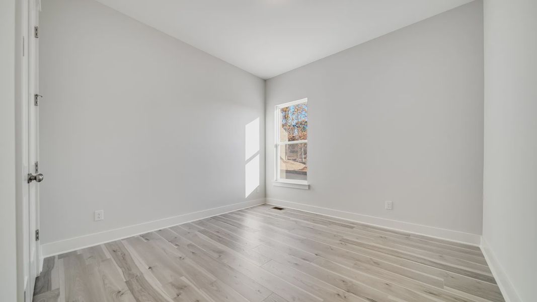 Secondary bedroom with hard-surface flooring and large window