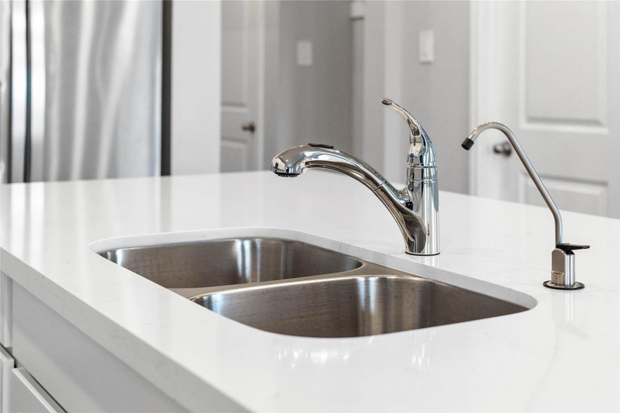 This contemporary double-bowl undermount sink integrates perfectly with the quartz countertop. Moen Integra faucet with DuPure drinking water system.