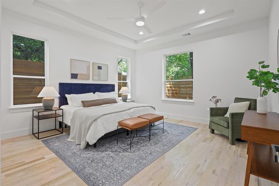 Bedroom featuring ceiling fan, light wood-type flooring, and a tray ceiling