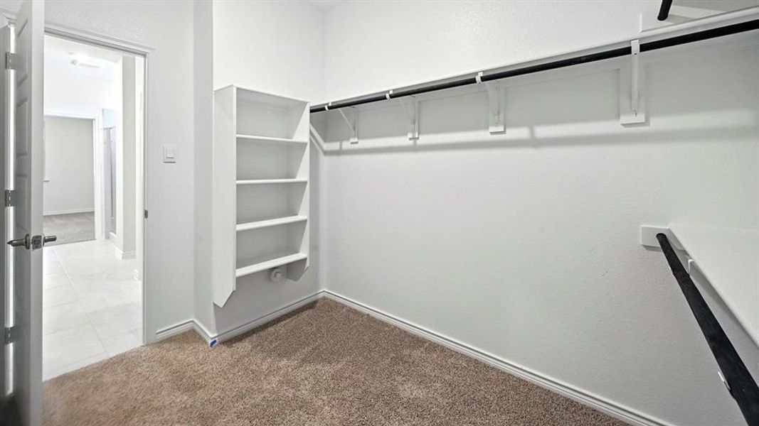 Walk in closet with dark carpet and dark tile patterned flooring Walk in closet with dark carpet and dark tile patterned flooring