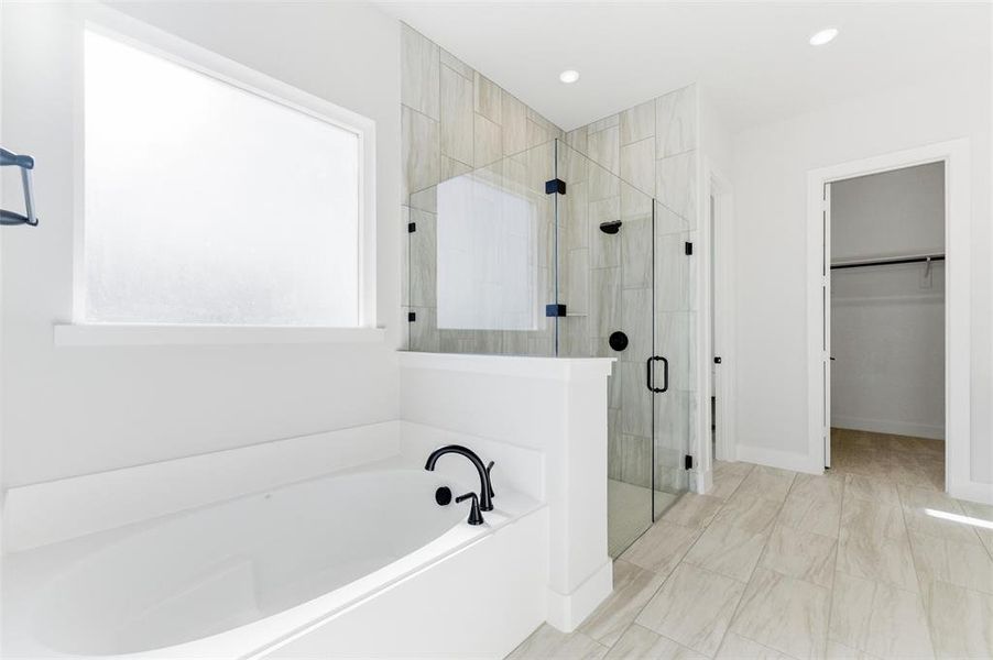 Bathroom featuring a spacious closet, a garden tub, a shower stall, and recessed lighting