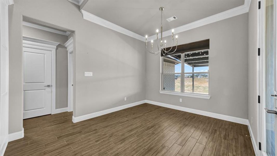 Unfurnished dining area with crown molding, wood-type flooring, and an inviting chandelier