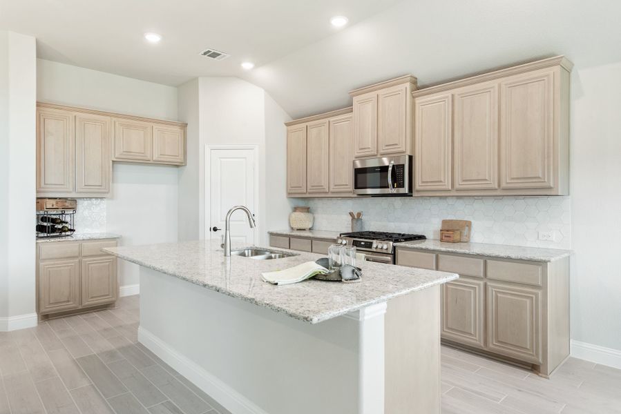 Kitchen with light wood cabinets, granite island with sink, and stainless steel appliances on tile floors Kitchen with light wood cabinets, granite island with sink, and stainless steel appliances on tile floors