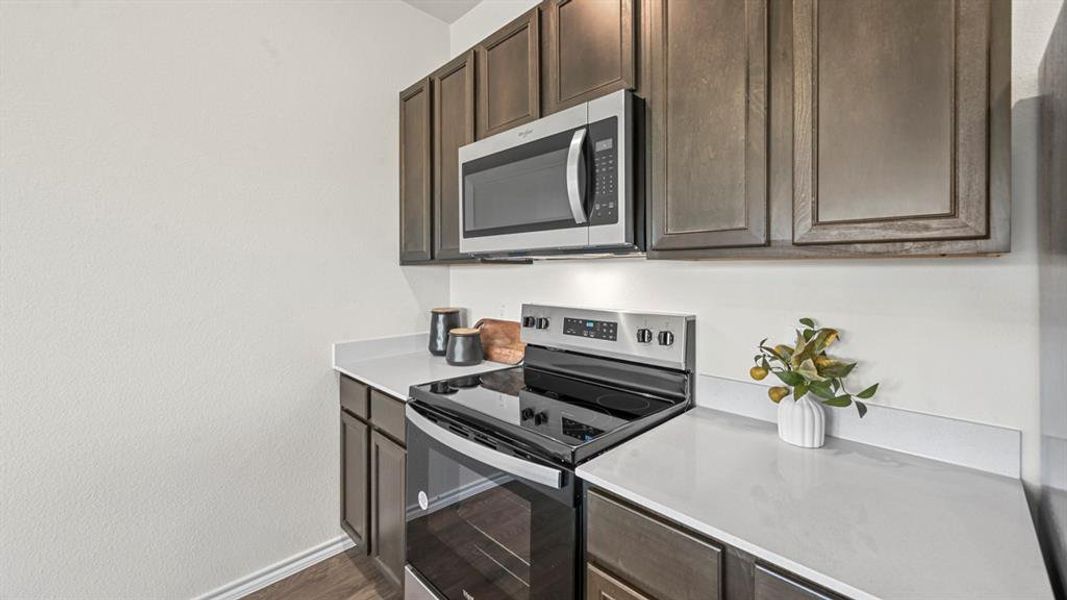 Kitchen with stainless steel appliances, dark brown cabinets, and dark wood-type flooring