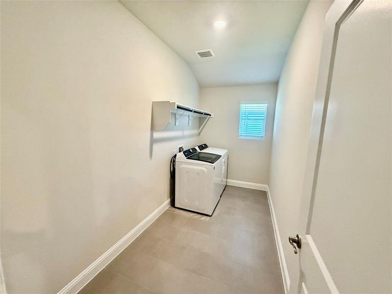 Dedicated utility room featuring tile flooring, a single window with blinds, and built-in shelving Dedicated utility room featuring tile flooring, a single window with blinds, and built-in shelving
