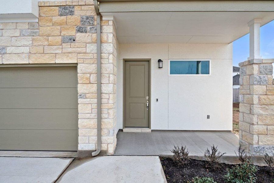 Entrance to property featuring stone siding and a garage