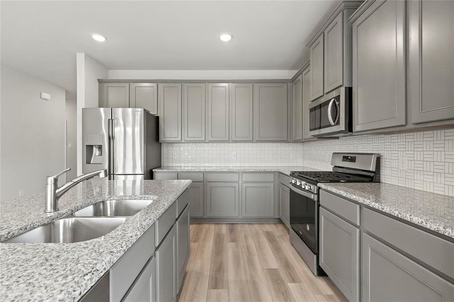 Kitchen featuring sink, light hardwood / wood-style flooring, stainless steel appliances, and backsplash
