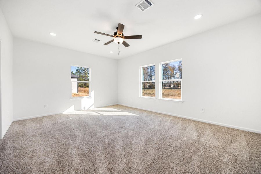 Spacious primary bedroom with abundant natural light, soft carpeting, and a modern ceiling fan for comfort and style. Spacious primary bedroom with abundant natural light, soft carpeting, and a modern ceiling fan for comfort and style.