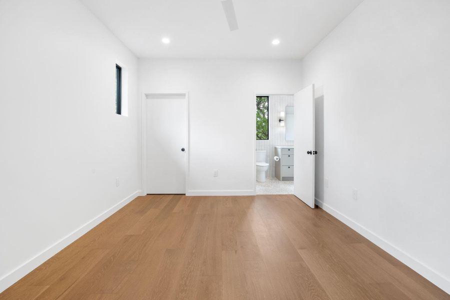 Unfurnished bedroom with connected bathroom, wood finished floors, a ceiling fan, and recessed lighting