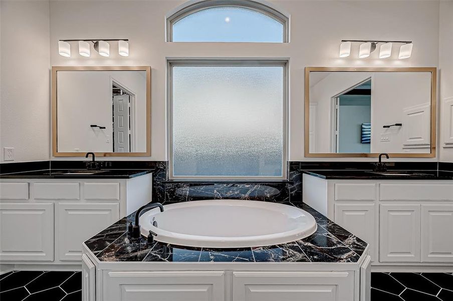 The spa-like ensuite features a freestanding soaking tub, a massive walk-in shower, dual vanities, and a custom closet designed by Closet Factory with display cabinets and a central island.