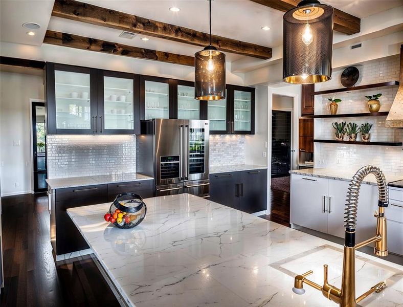 Kitchen with beamed ceiling, light stone countertops, tasteful backsplash, and stainless steel fridge with ice dispenser