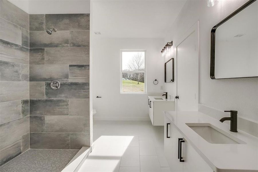 Bathroom with vanity, a tile shower, and tile patterned flooring Bathroom with vanity, a tile shower, and tile patterned flooring