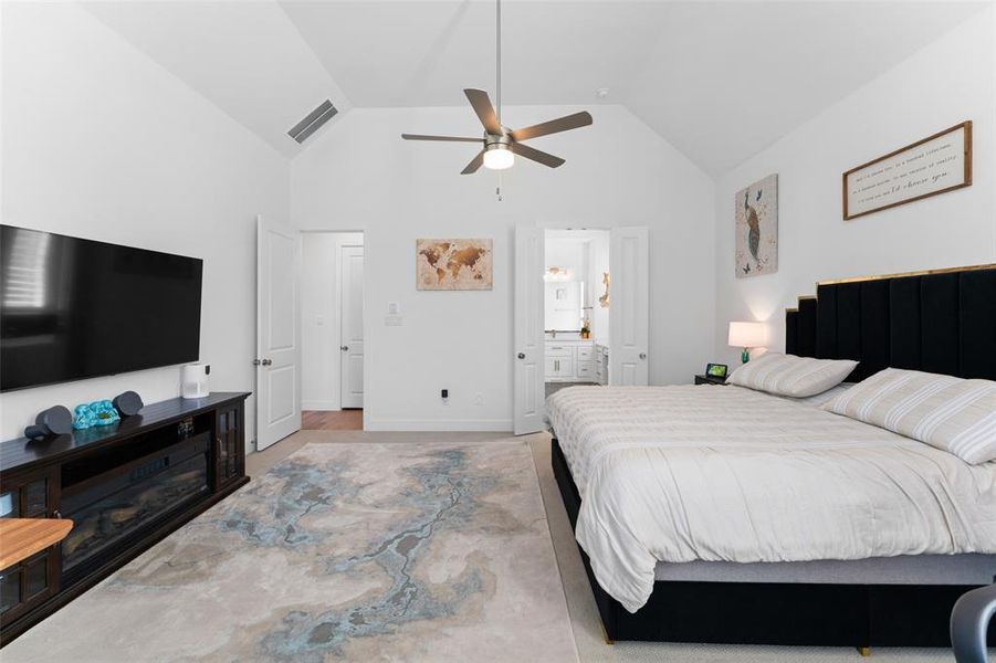 This room features vaulted ceilings, a ceiling fan, and a light-colored rug with a distinct pattern