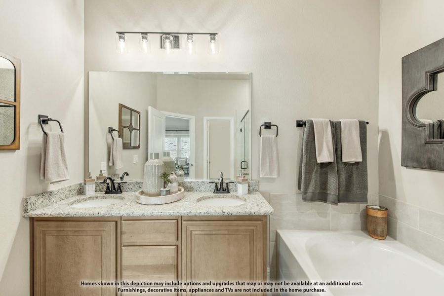 Bathroom with double sink vanity, granite countertop, wood cabinets, large mirror, and soaking tub