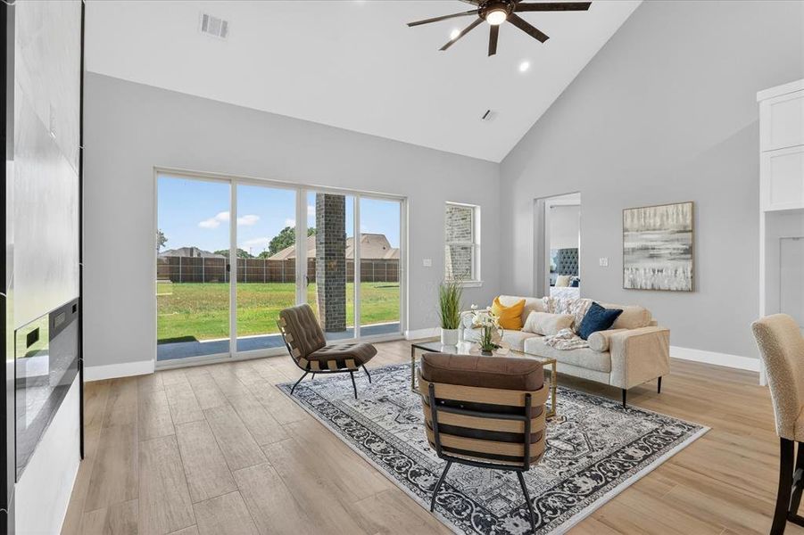 Spacious living area featuring a vaulted ceiling with a ceiling fan, recessed lighting, and light wood-finish flooring