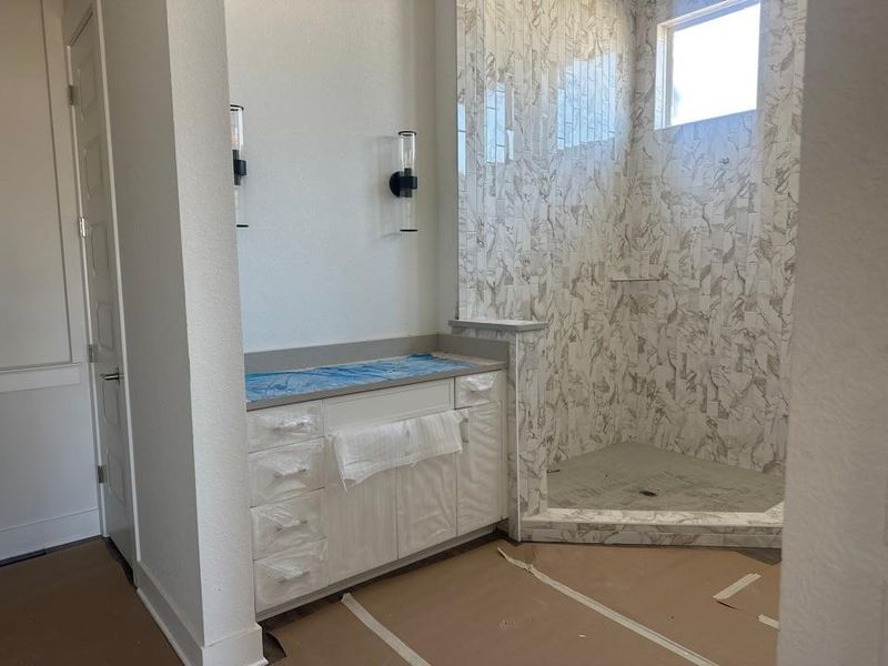 Bathroom with a shower stall and a textured wall Bathroom with a shower stall and a textured wall