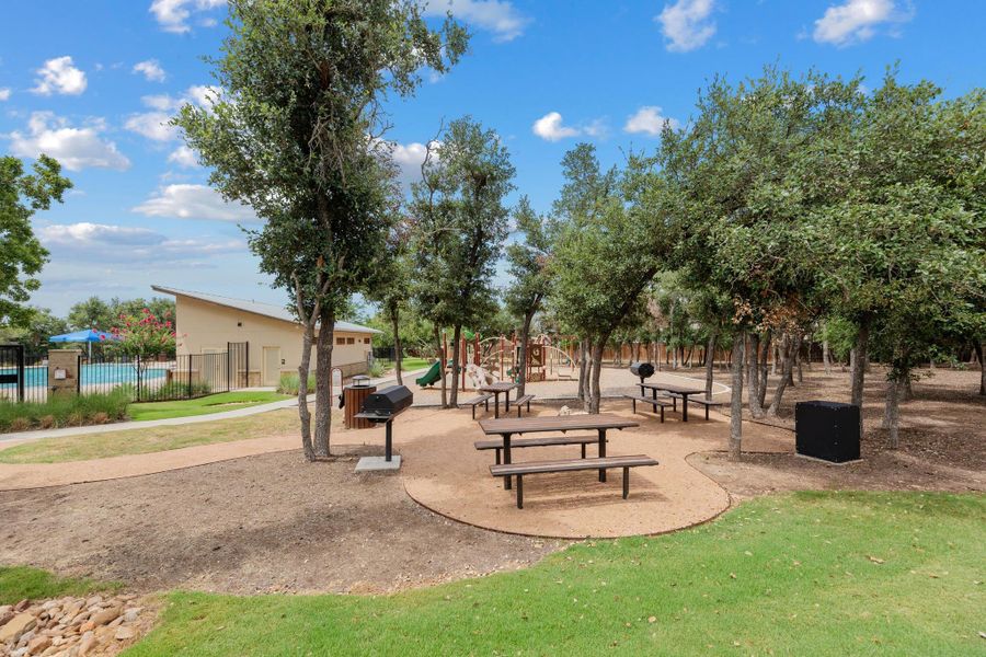The community recreation area features picnic tables and grills, nestled amongst mature trees, with a playground and pool. The community recreation area features picnic tables and grills, nestled amongst mature trees, with a playground and pool.