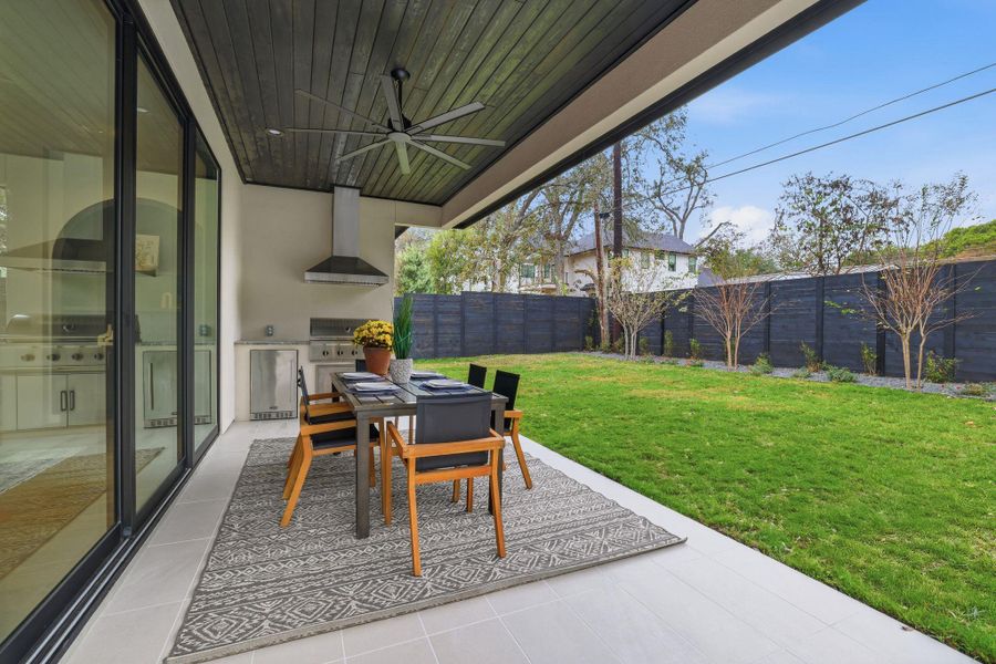 Fenced backyard featuring a patio area, ceiling fan, area for grilling, and outdoor dining area