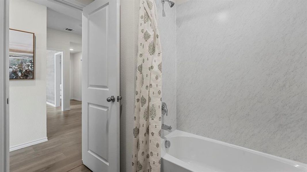 Bathroom featuring a white bathtub, a shower with a showerhead and faucet, and a patterned shower curtain
