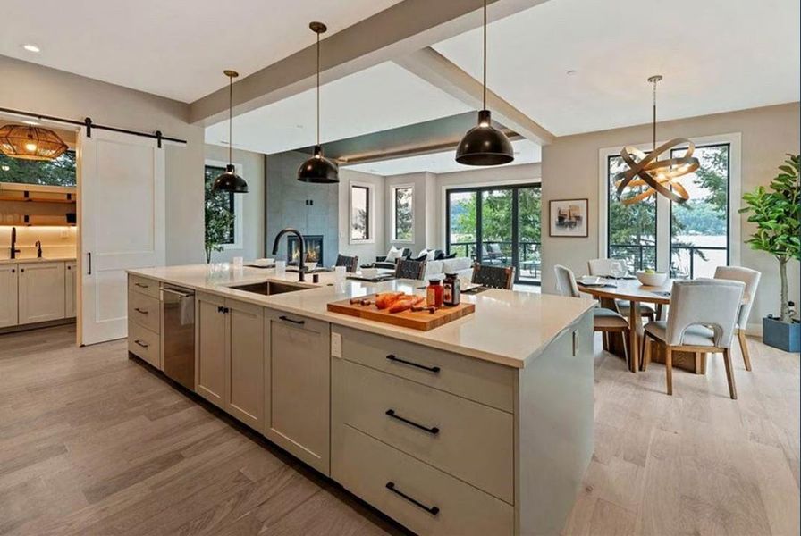 Kitchen with pendant lighting, a barn door, a kitchen island with sink, and light wood finished floors