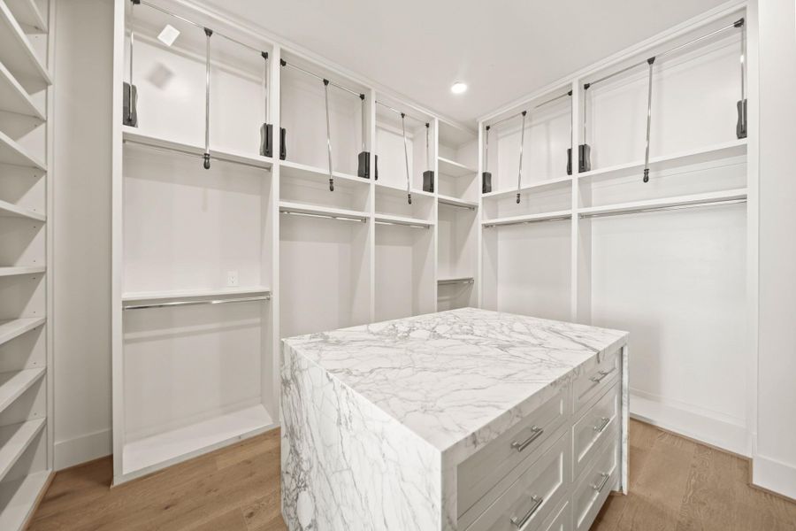 One of TWO closets fitting all your needs. Custom display cabinetry, pull downs for those hard to reach shelves, and a custom drawer island with a quartzite waterfall countertop.