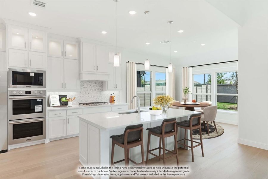 White kitchen with large island, bar seating, double oven, and open dining area with large windows