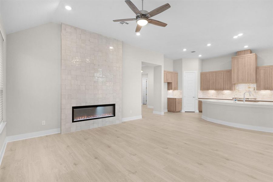 Unfurnished living room with recessed lighting, ceiling fan, light wood finished floors, and a tiled fireplace Unfurnished living room with recessed lighting, ceiling fan, light wood finished floors, and a tiled fireplace