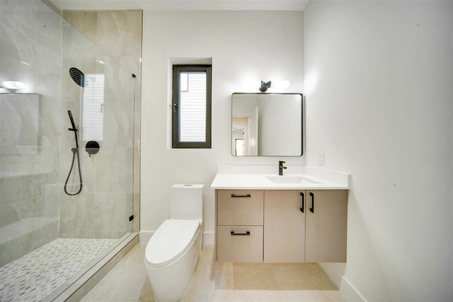 Bathroom featuring tiled shower, vanity, toilet, and tile patterned flooring